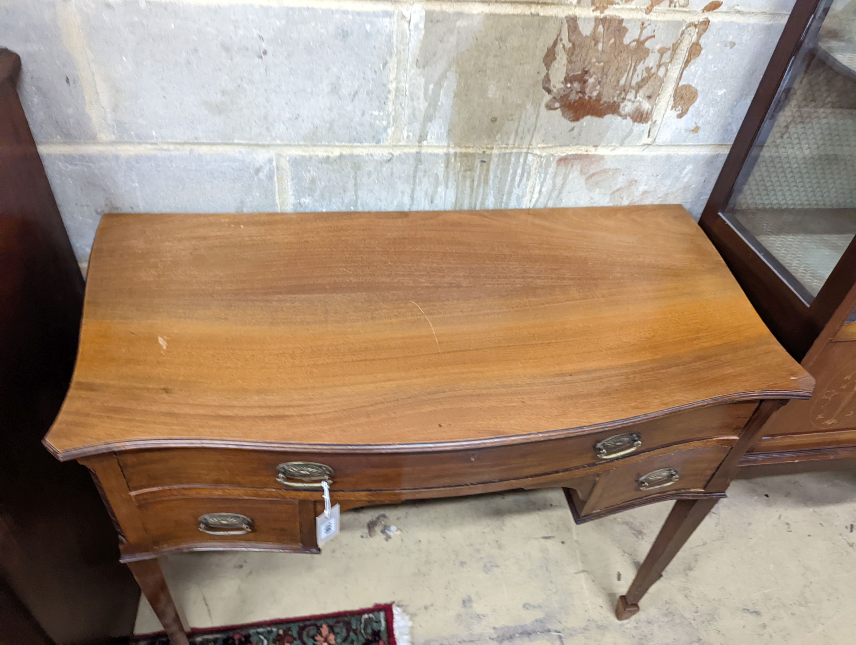An Edwardian mahogany serpentine kneehole dressing table. W-106cm, D-53cm, H-79cm.